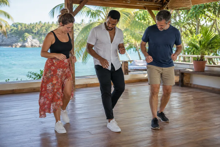 Profesor demostrando el juego de pies de bachata a dos principiantes