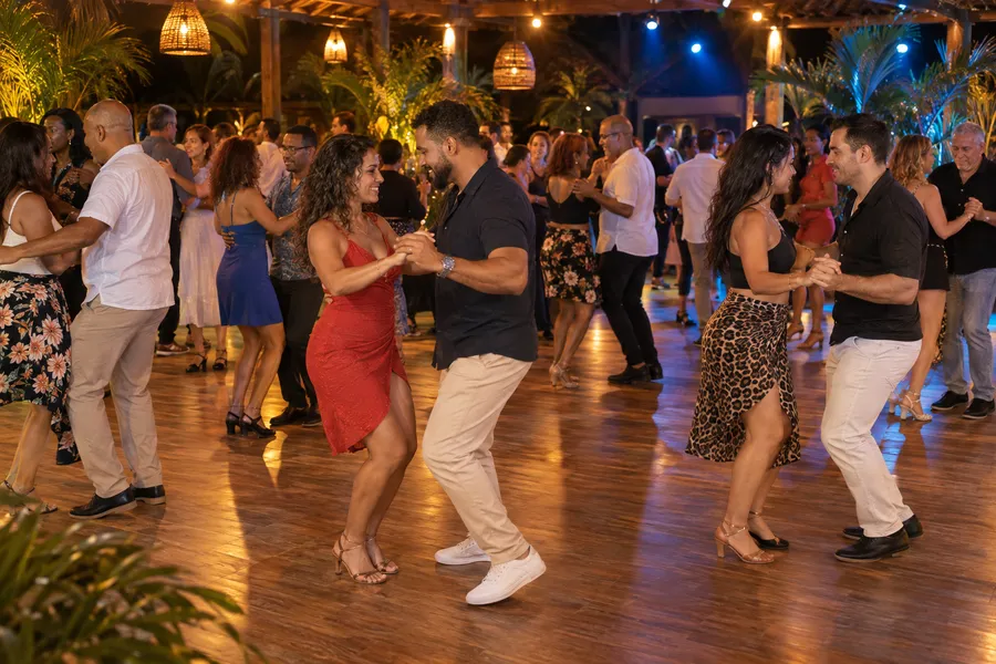 Parejas de bachata en una pista de madera concurrida bajo luces ámbar y azules de festival